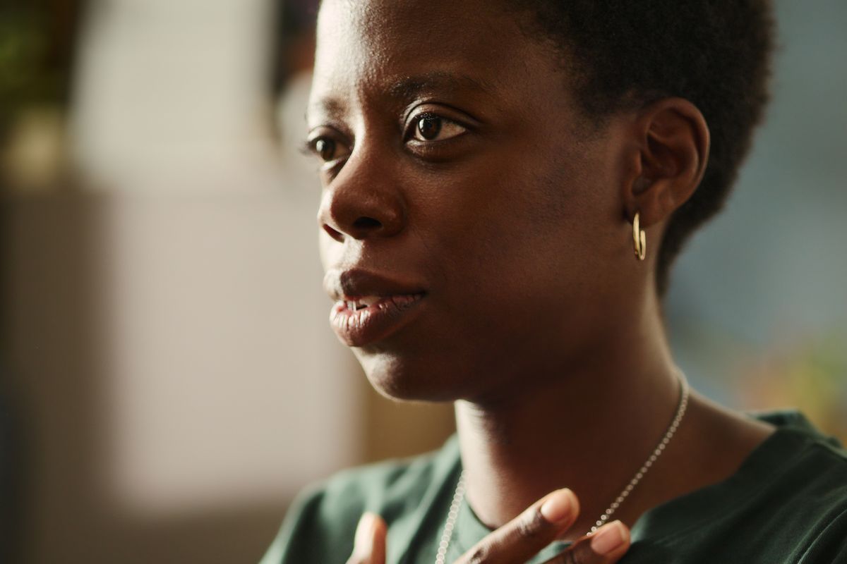 A woman rests a hand on her chest and takes a slow breath.